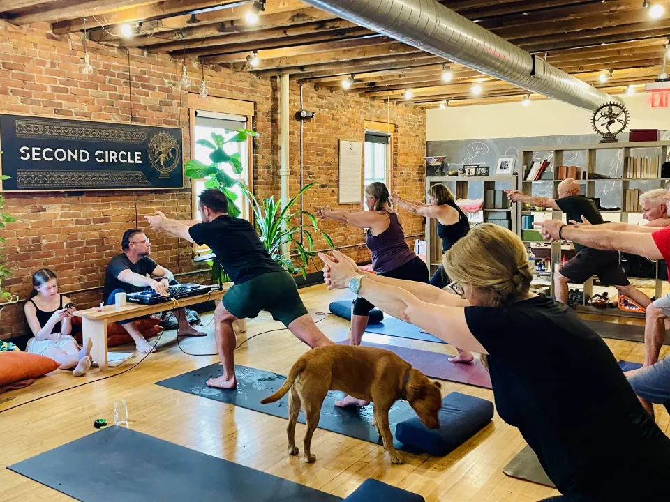 A full class in the studio with a dog trotting between the mats